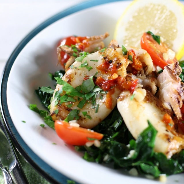 Grilled squid with fried spinach and little tomatoes